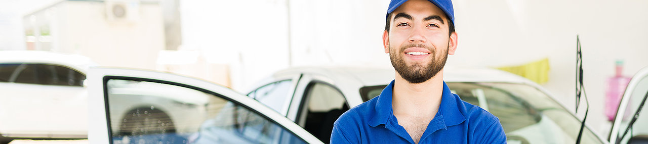 Employee of a car wash smiling on a summer day as they work.