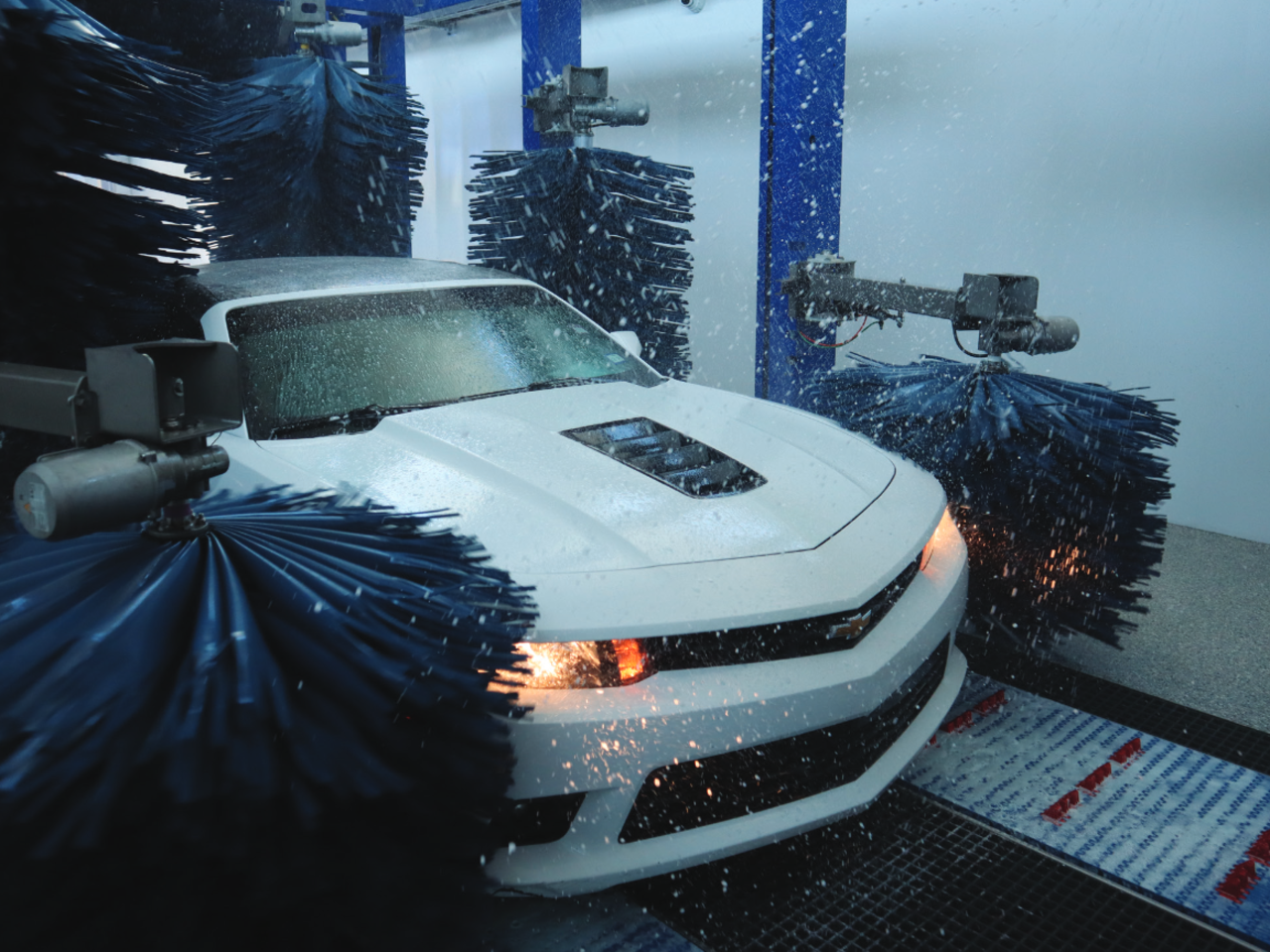 A white car going through a Mark VII SoftLine Tunnel with wheel cleaner options.